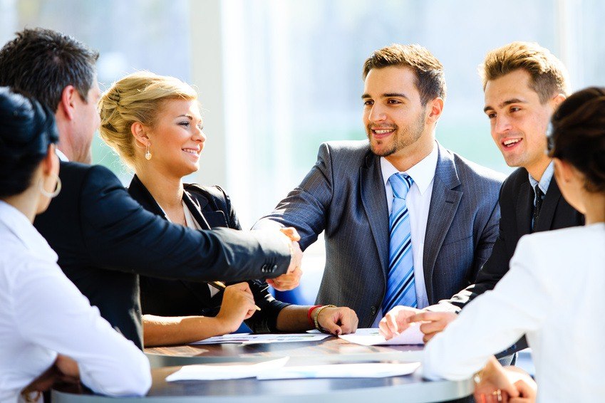 men in suits shaking hands at table