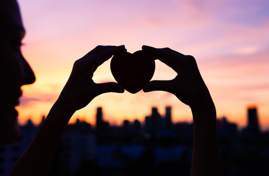 woman holding heart during sunset