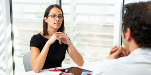 woman at table with tablet interviewing man